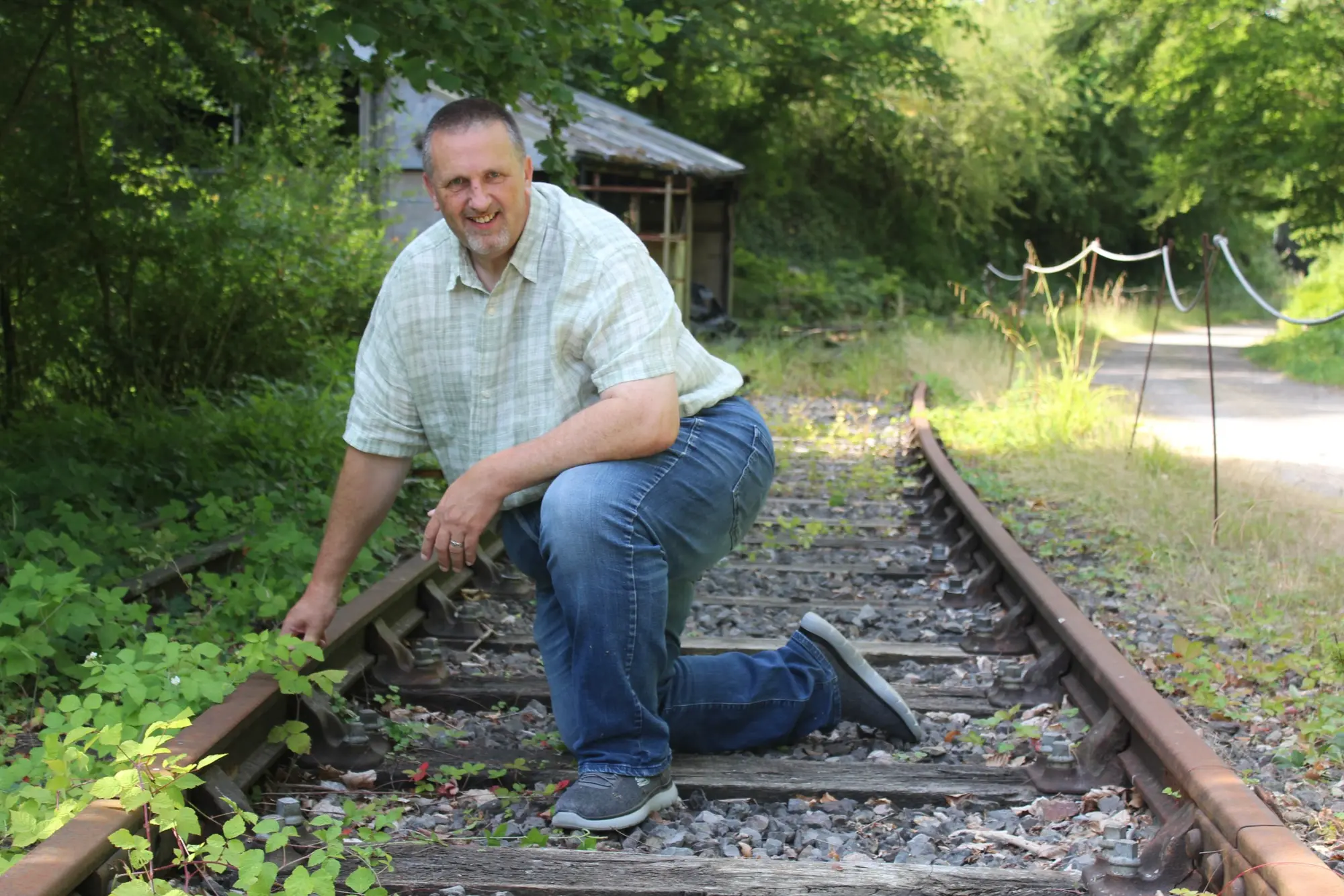 Chris Kirk examining a surviving railway line in a wooded landscape
